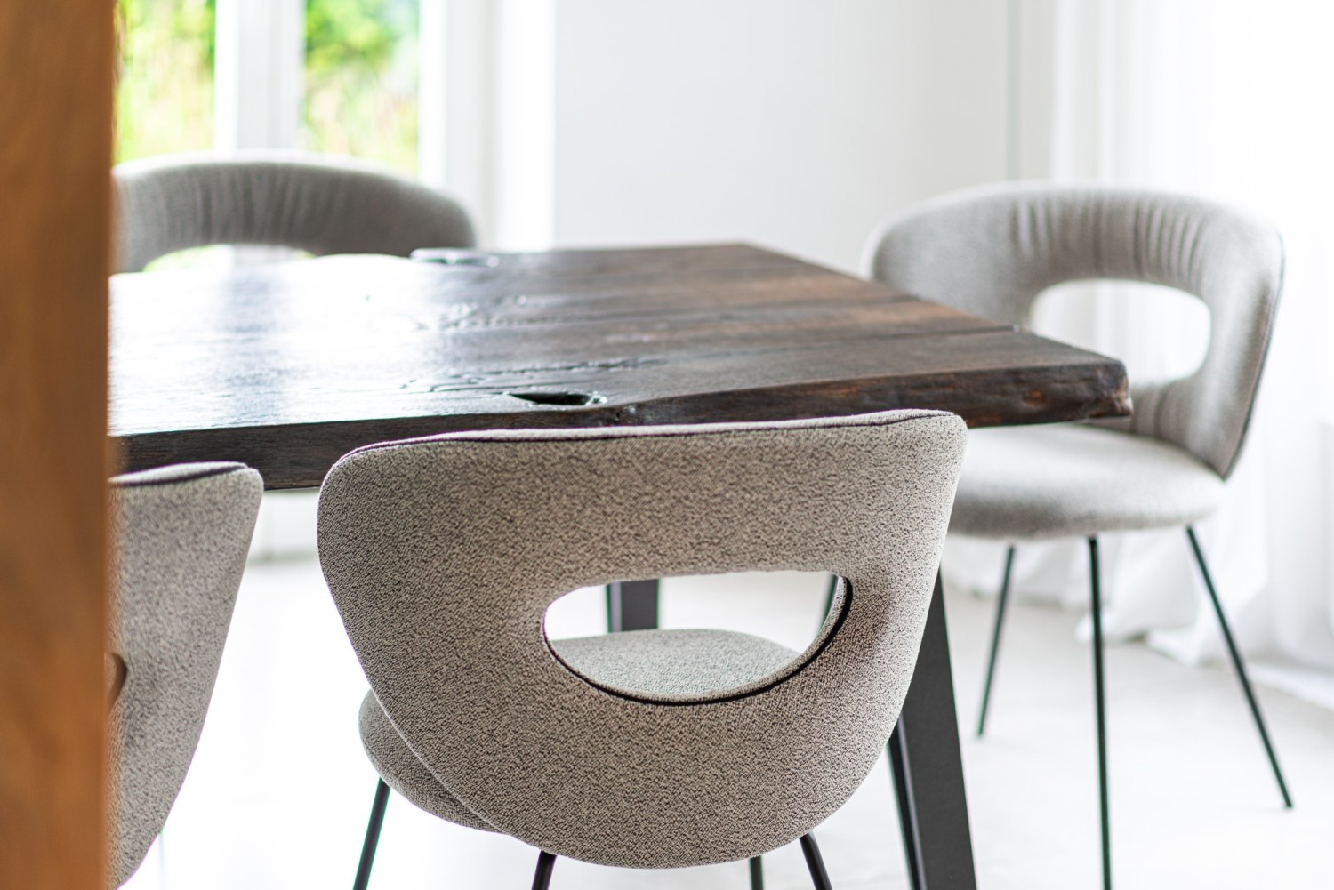 ALICE Stühle in grauem Rohi-Stoff stehen um den schwarzen ASCO Nightingale Tisch.