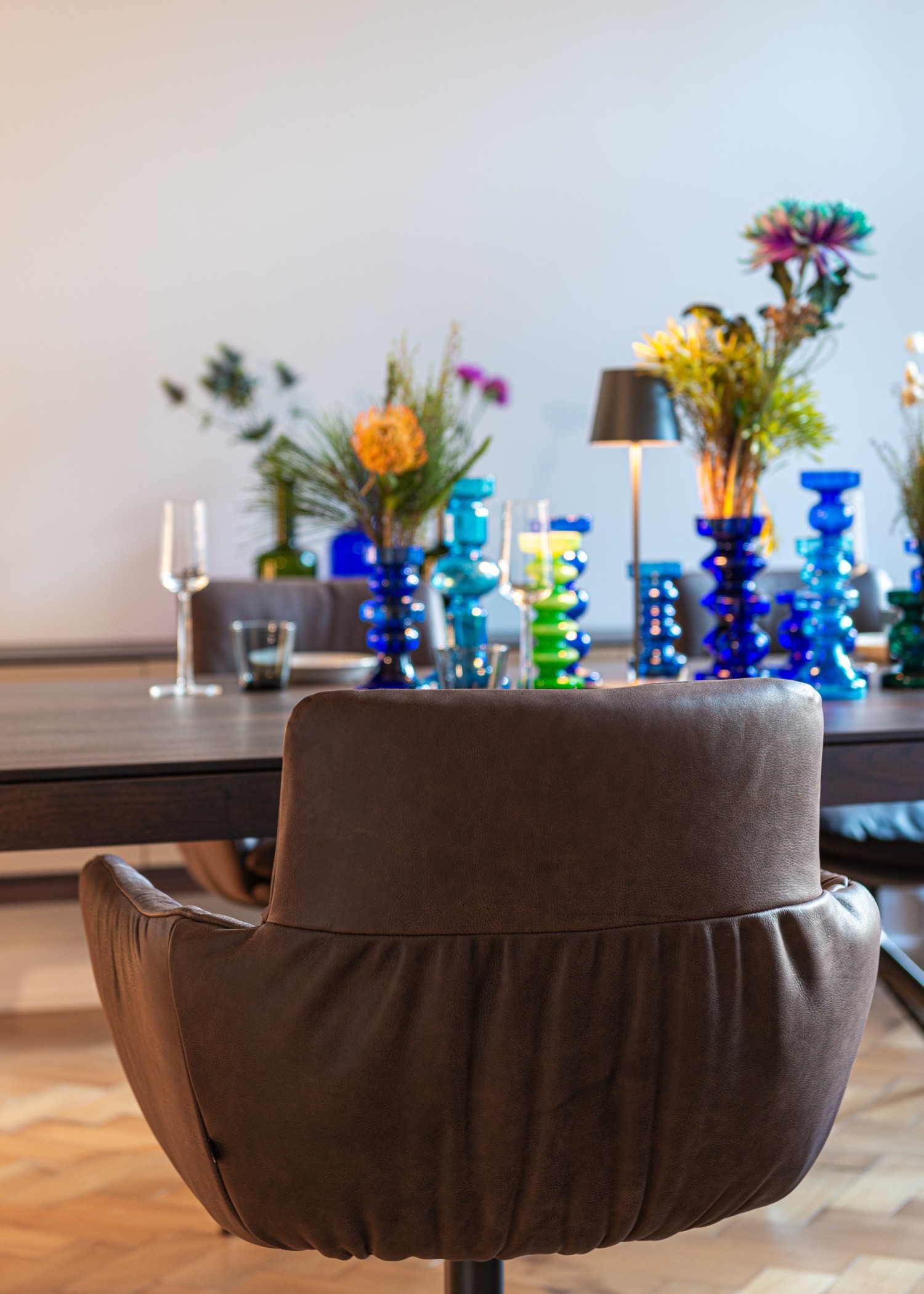 FAYE CASUAL chair in brown leather on a swivel base at the ASCO Aereo table in walnut