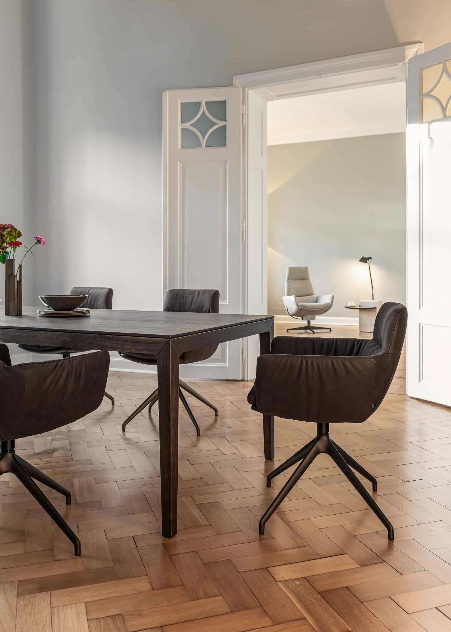 FAYE CASUAL chair in brown leather on a swivel base at the ASCO Aereo table in walnut